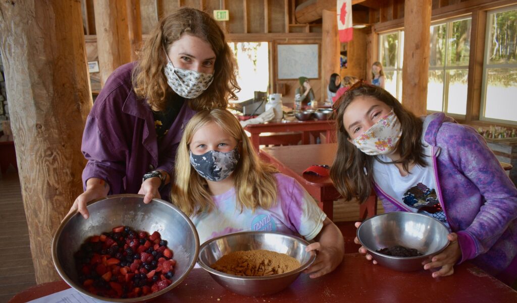 A staff member and two campers display their pie ingredients on 4th of July