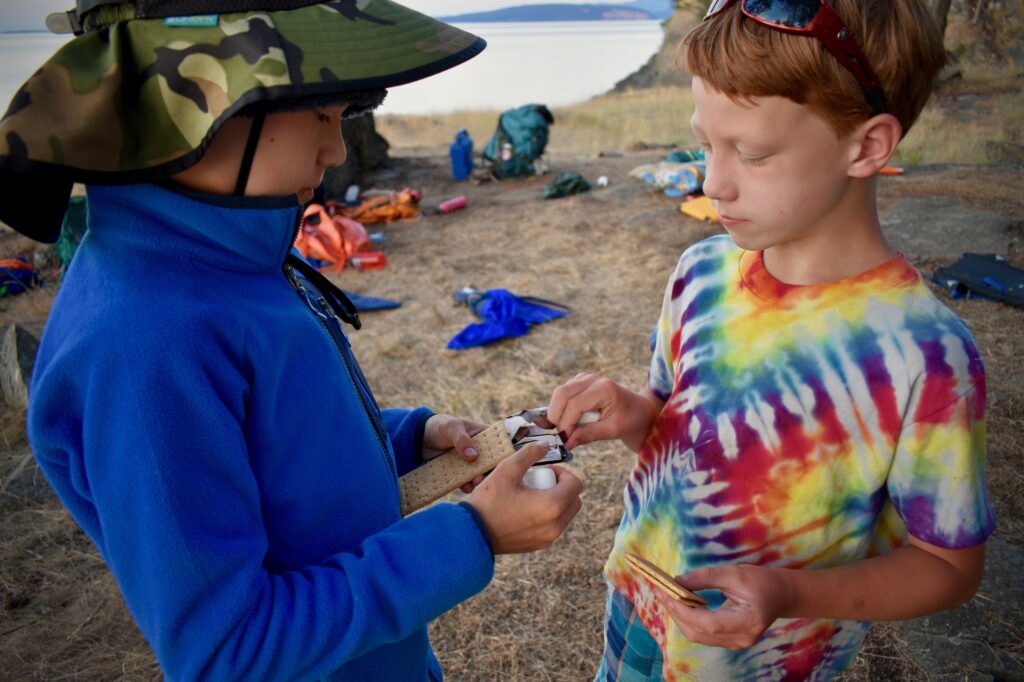 Close-up of two young campers sharing graham crackers, marshmallows, and chocolate bars
