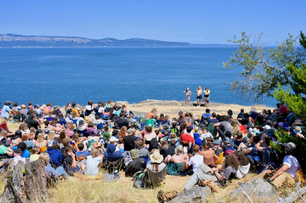 Large group of campers gathered at Chapel Rock with the ocean in the background