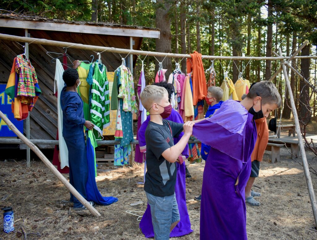 Campers dressed in bright colors select brightly-colored costumes from an outdoor clothing rack